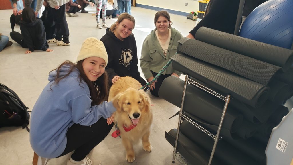 Students pose with Golden Retriever therapy dog, all smiles!